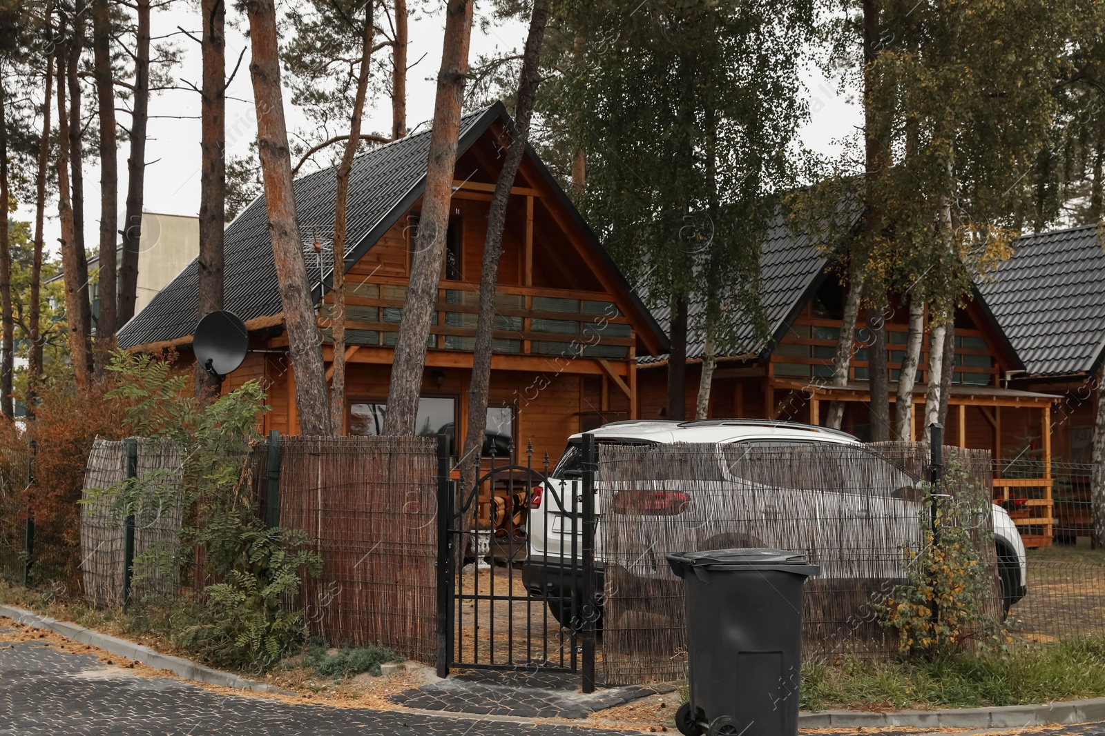 Photo of Cottage houses near trees for rent and parked car outdoors. Real estate