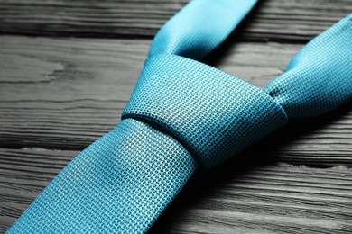 Photo of One light blue necktie on black wooden table, closeup