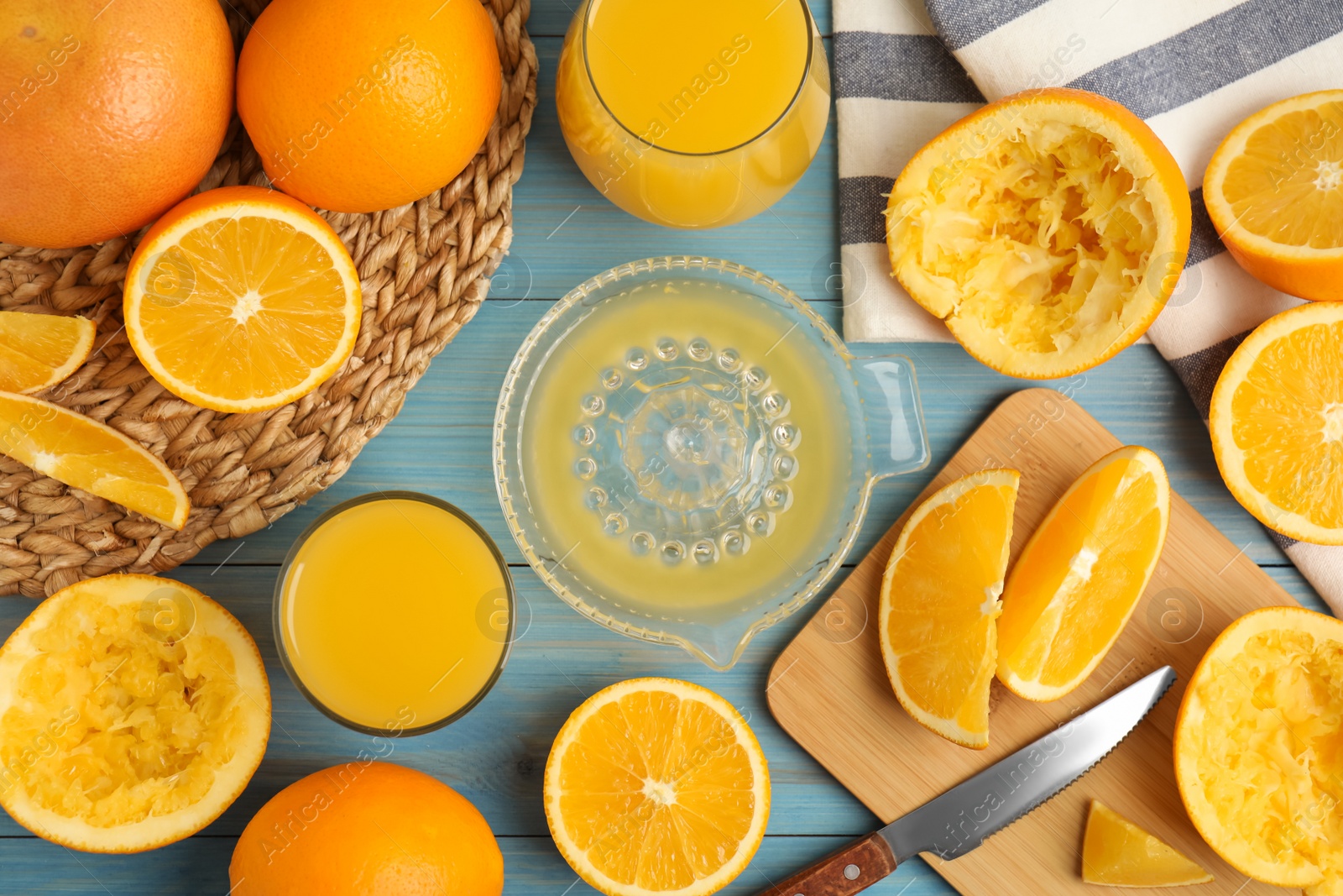 Photo of Freshly made juice, oranges and squeezer on blue wooden table, flat lay