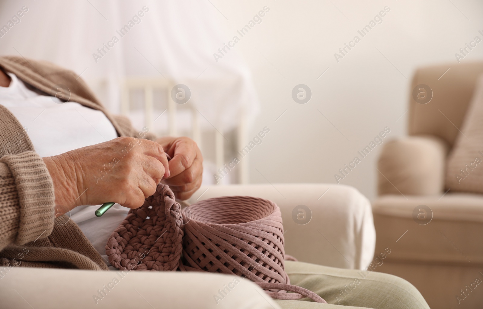 Photo of Elderly woman crocheting at home, closeup. Creative hobby