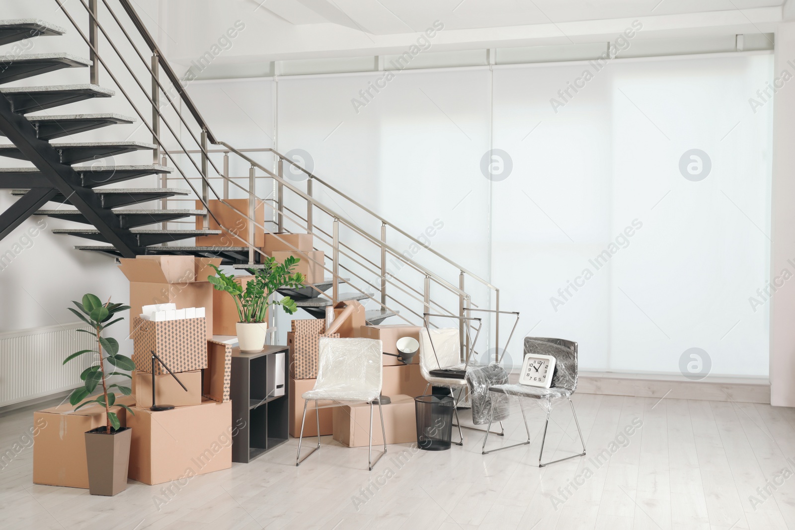 Photo of Cardboard boxes and packed stuff near stairs in office, space for text. Moving day