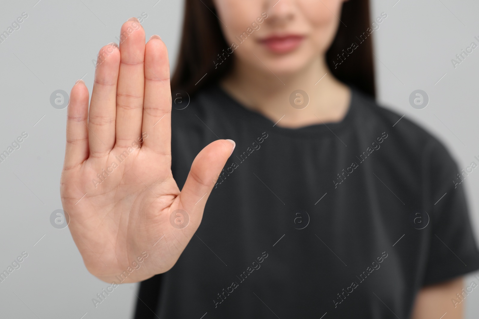 Photo of Woman showing stop gesture on grey background, closeup. Space for text