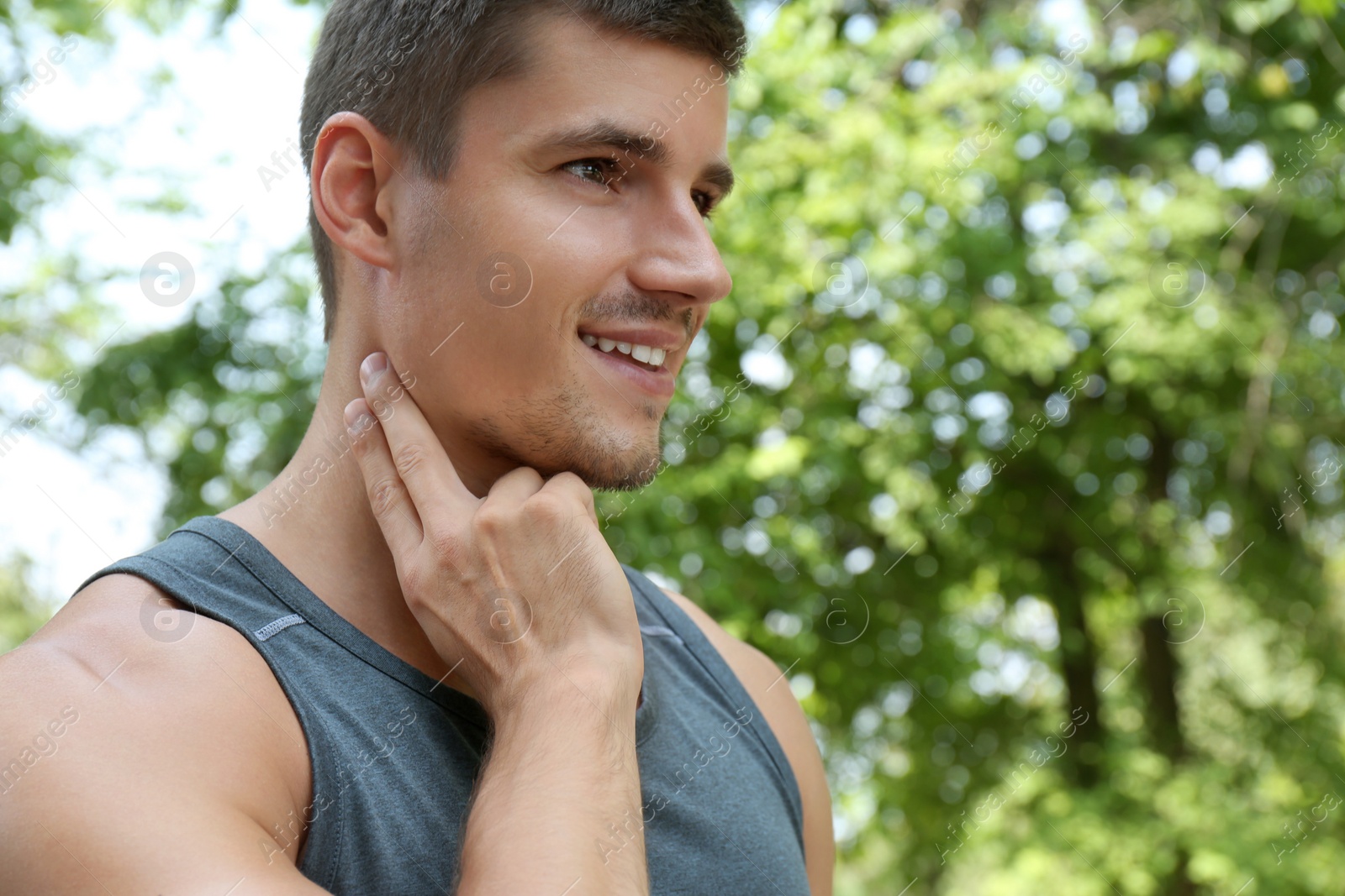 Photo of Young man checking pulse after training outdoors