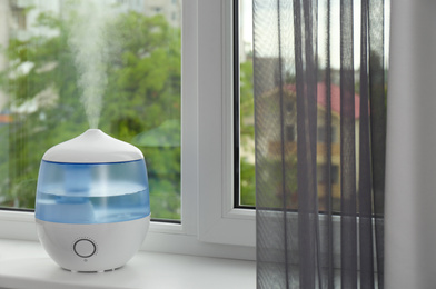 Modern air humidifier on windowsill indoors. Space for text