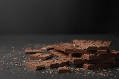 Photo of Pieces of tasty chocolate bars on grey table, space for text