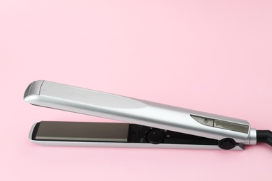 Photo of Modern hair iron for straightening on color background