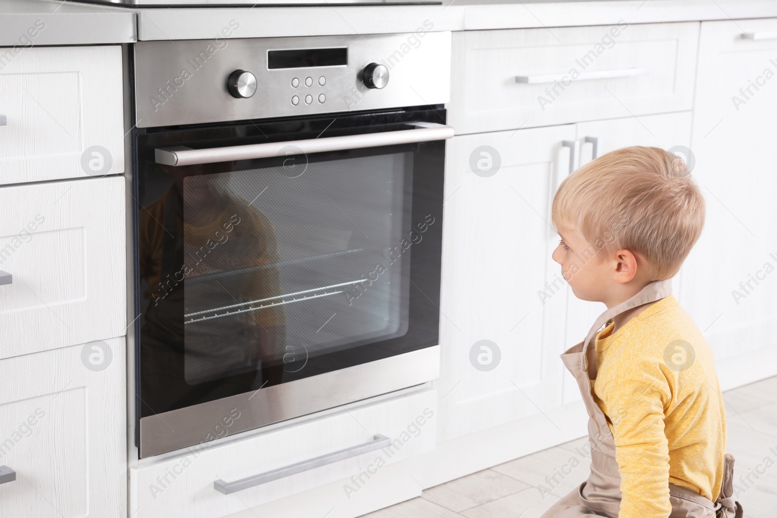 Photo of Little boy baking something in oven at home