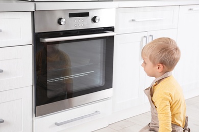 Little boy baking something in oven at home