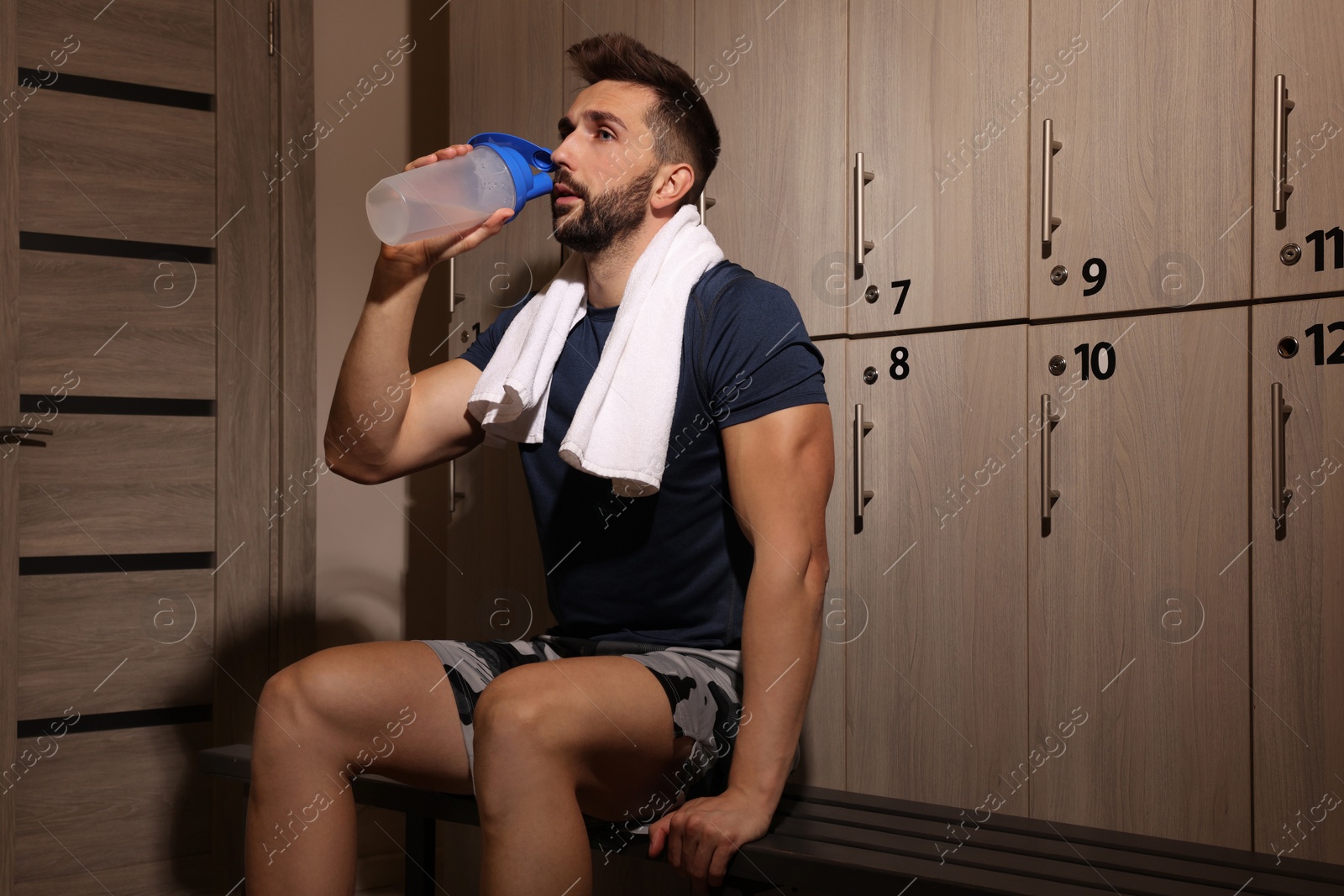 Photo of Handsome man drinking water in locker room