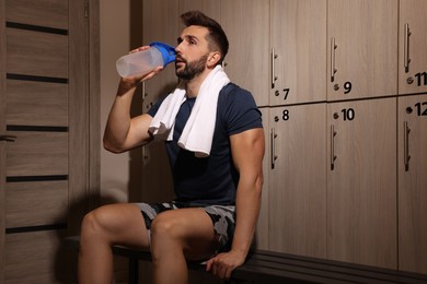 Handsome man drinking water in locker room