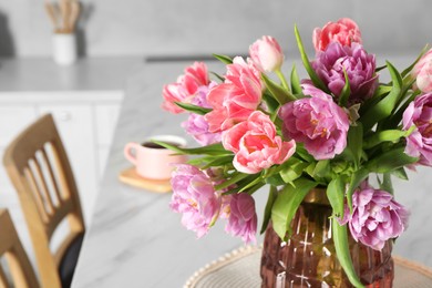 Photo of Beautiful bouquet of colorful tulip flowers on white marble table in kitchen, space for text