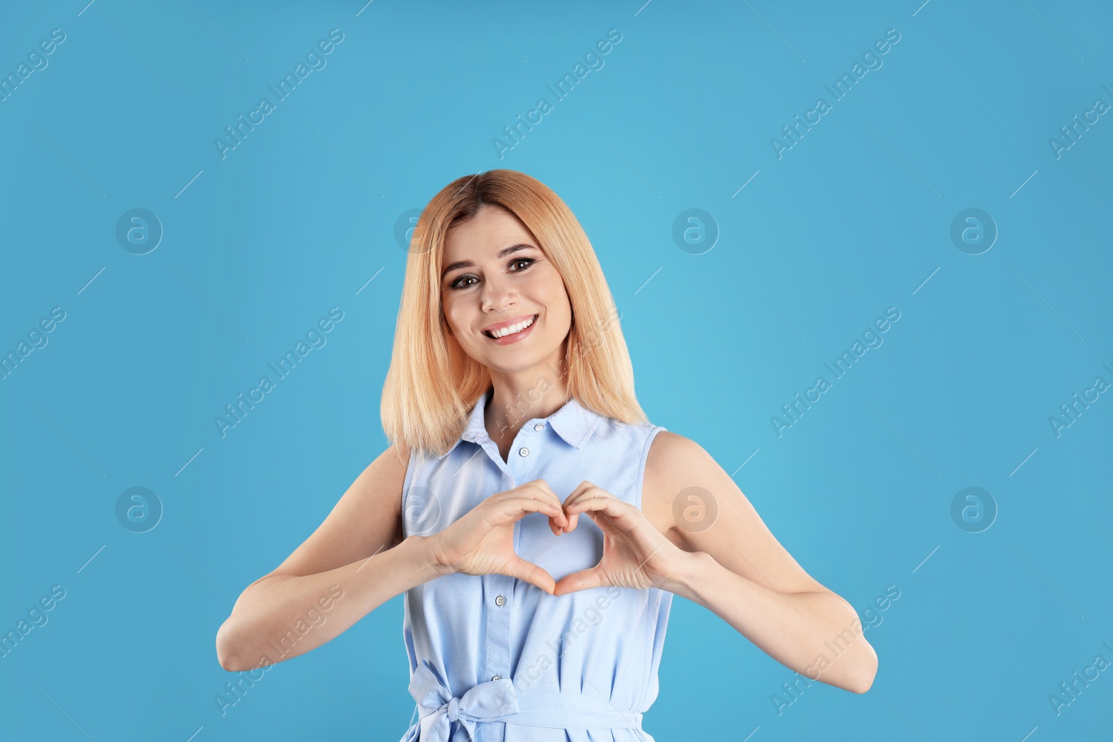 Photo of Portrait of woman making heart with her hands on color background