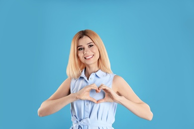 Photo of Portrait of woman making heart with her hands on color background