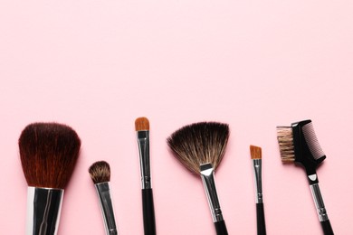 Photo of Different makeup brushes on pink background, flat lay. Space for text