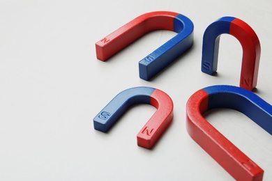 Red and blue horseshoe magnets on white background. Space for text