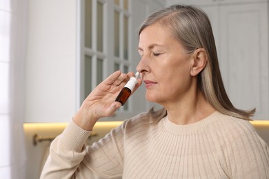 Photo of Medical drops. Woman using nasal spray indoors