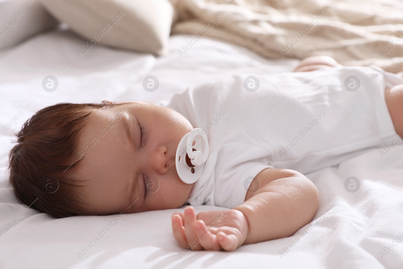 Photo of Cute little baby with pacifier sleeping on bed