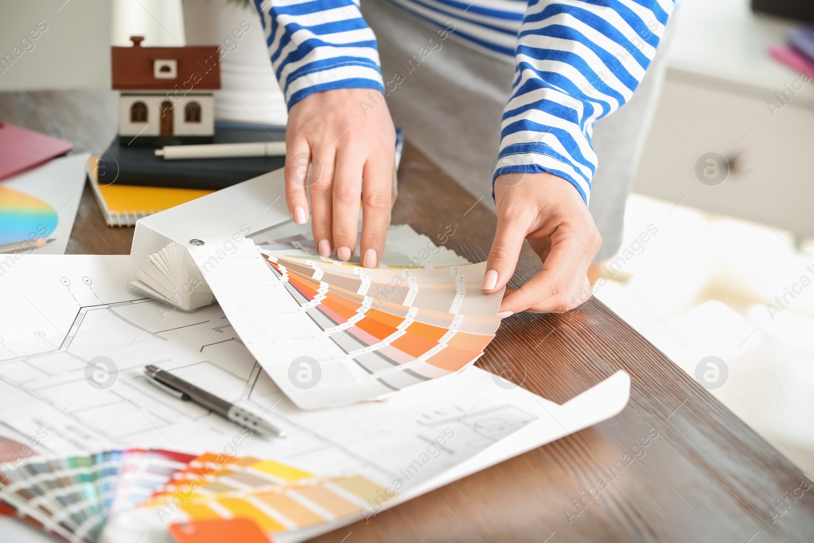 Photo of Female designer working with color palette samples at table