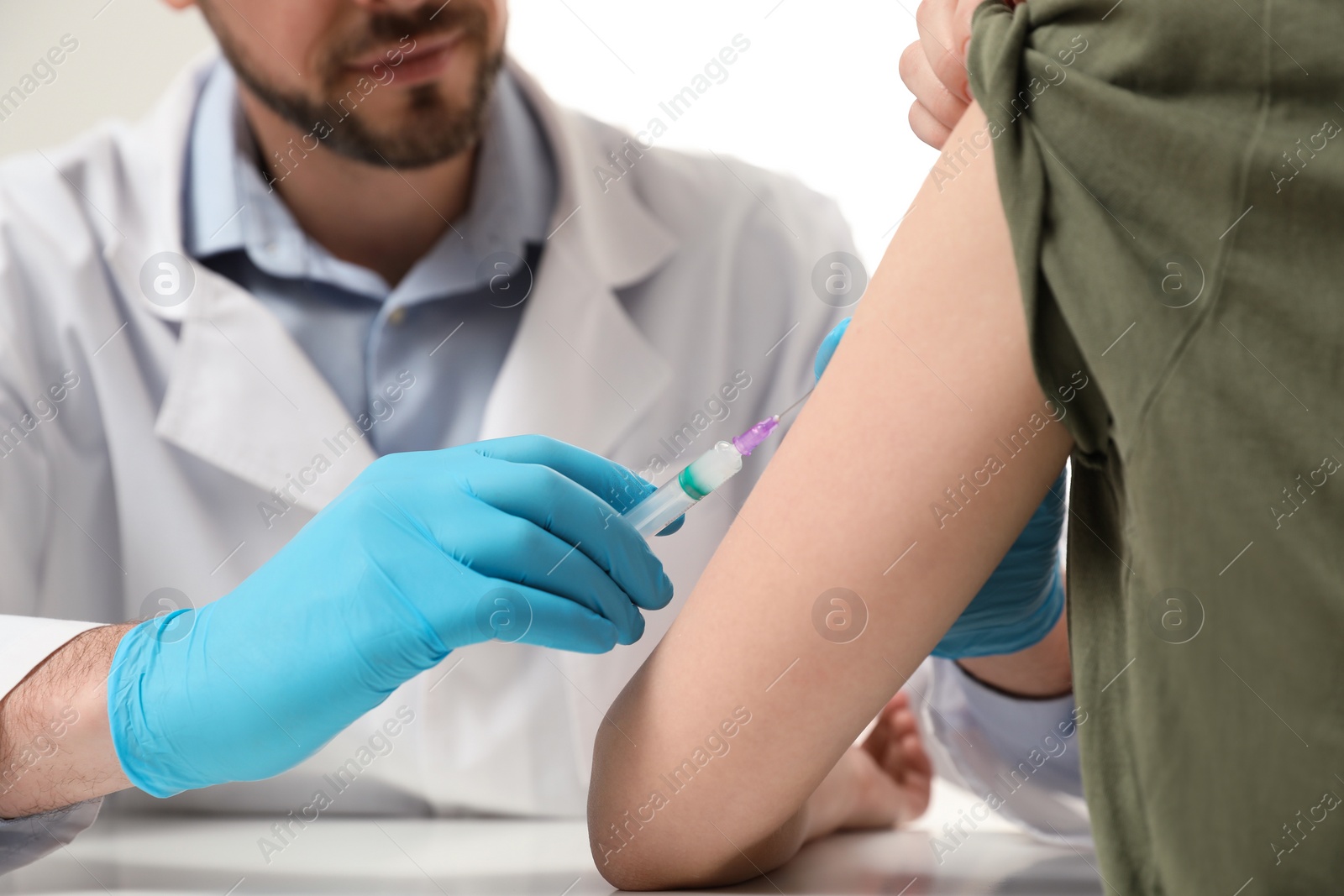 Photo of Doctor giving hepatitis vaccine to patient at table, closeup