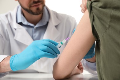 Doctor giving hepatitis vaccine to patient at table, closeup