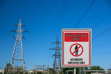 Sign with text Restricted Area Authorized Employees Only near high voltage towers outdoors