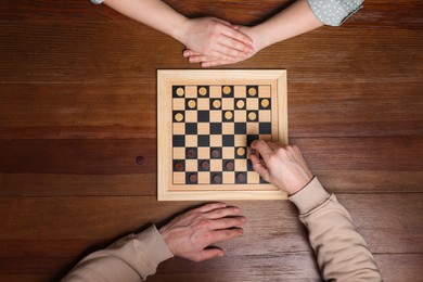 Man playing checkers with woman at wooden table, top view