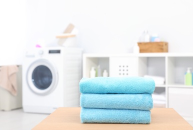 Stack of clean towels on table in bathroom.  Space for text