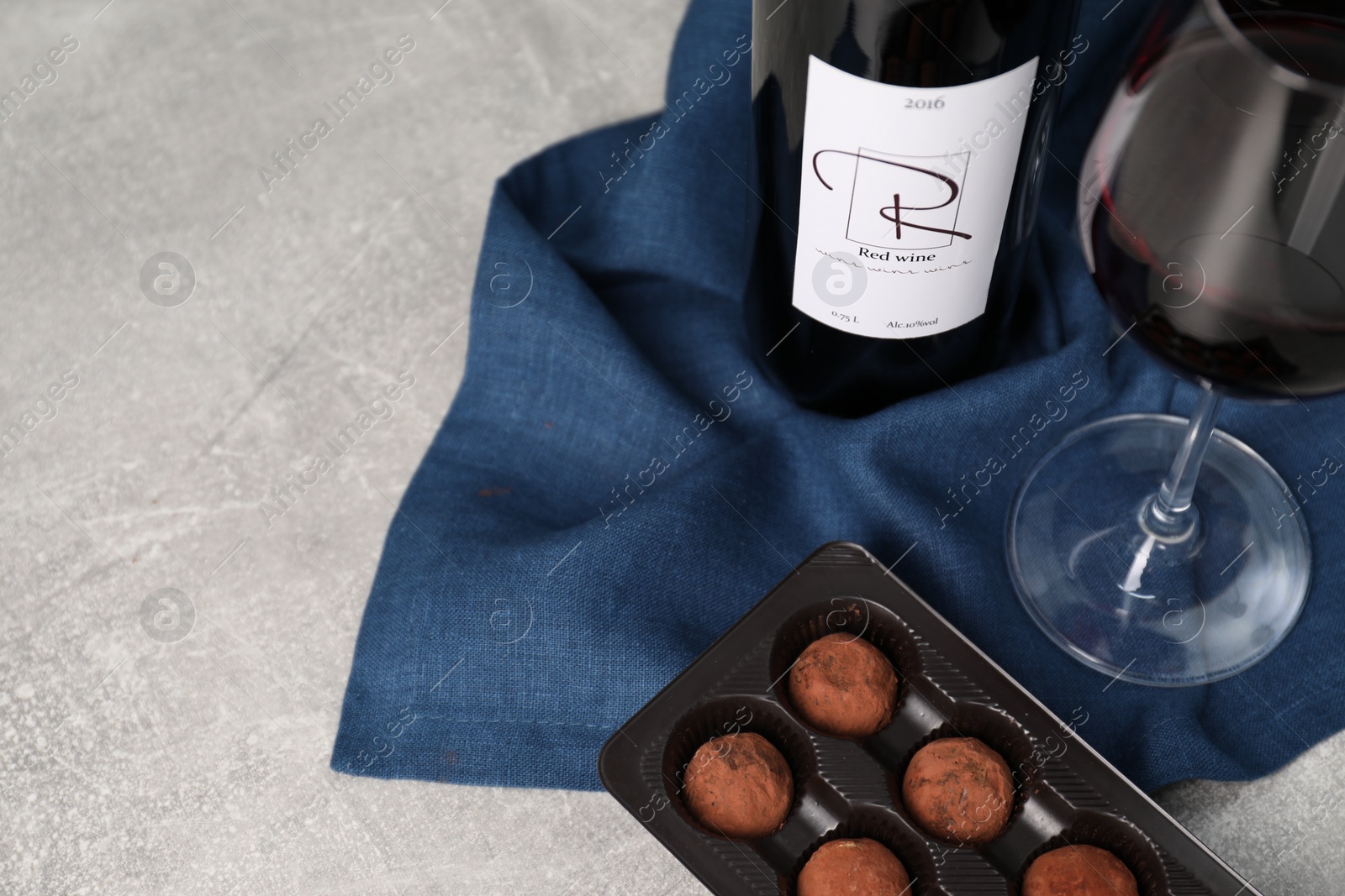 Photo of Red wine and chocolate truffles on light textured table. Space for text