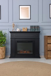 Photo of Black stylish fireplace with books and accessories in cosy living room