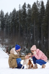Photo of Couple with dog near forest, space for text. Winter vacation