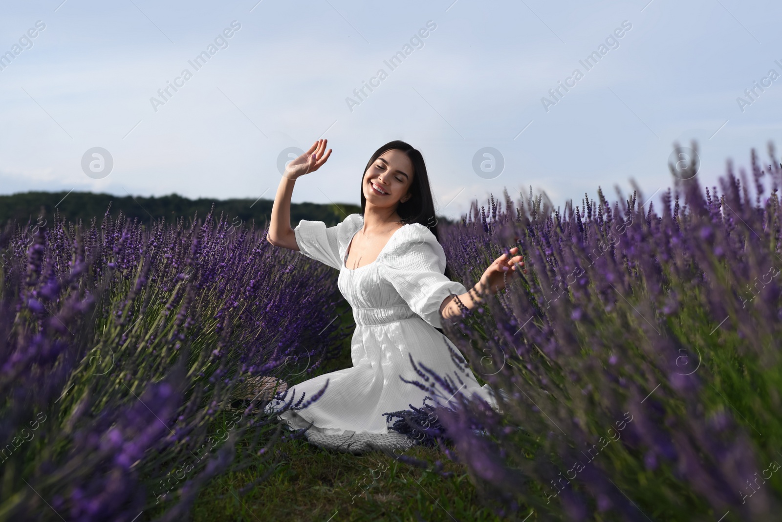 Photo of Beautiful young woman sitting in lavender field