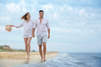 Happy couple having romantic walk on beach. Space for text