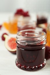 Photo of Open glass jar of sweet jam on white wooden table, closeup. Space for text