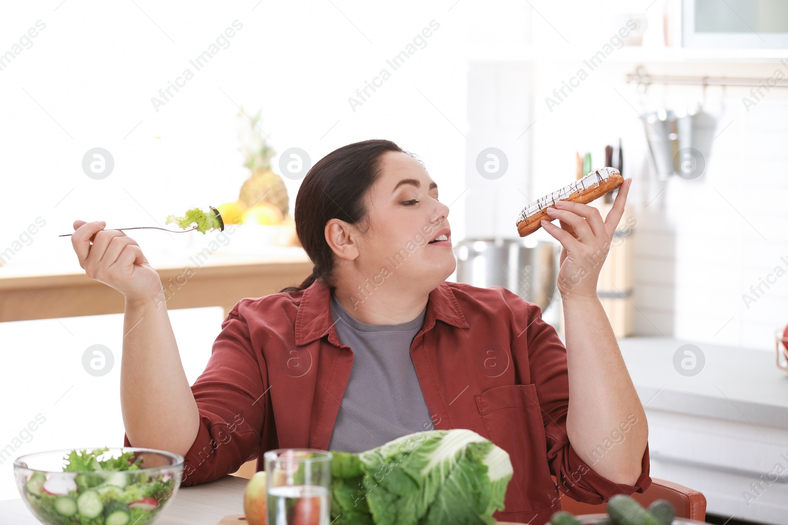 Photo of Woman choosing between vegetable salad and dessert in kitchen. Healthy diet