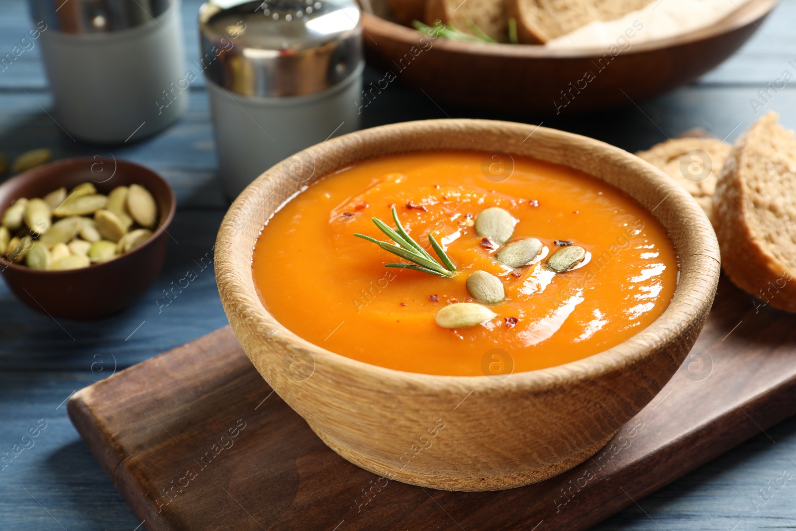 Photo of Board with bowl of sweet potato soup served on table