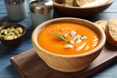 Board with bowl of sweet potato soup served on table