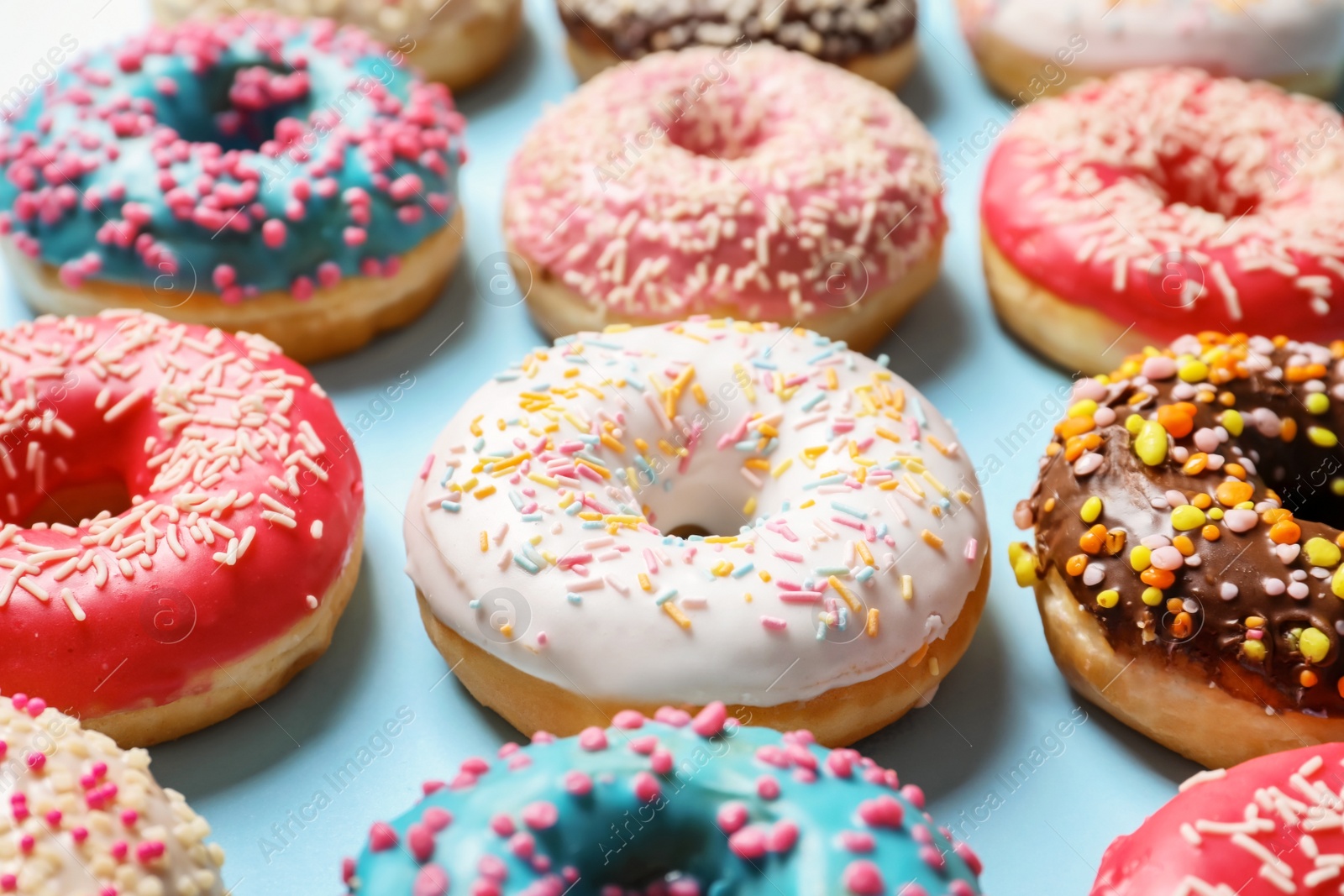 Photo of Delicious glazed doughnuts with sprinkles on color background