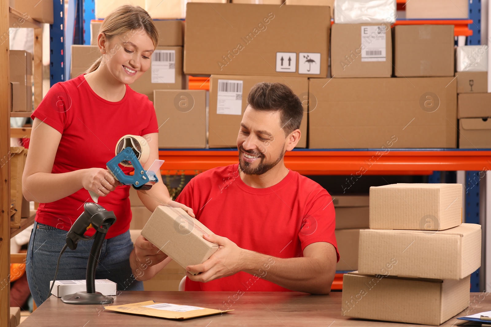 Photo of Post office workers packing parcel at counter indoors