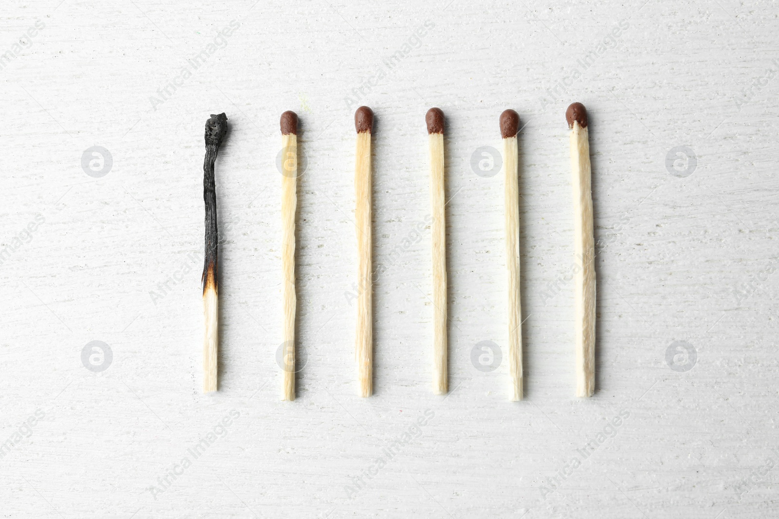 Photo of Used match among whole ones on wooden background, flat lay. Psychological burnout concept