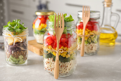 Photo of Glass jars with healthy meal on light grey marble table