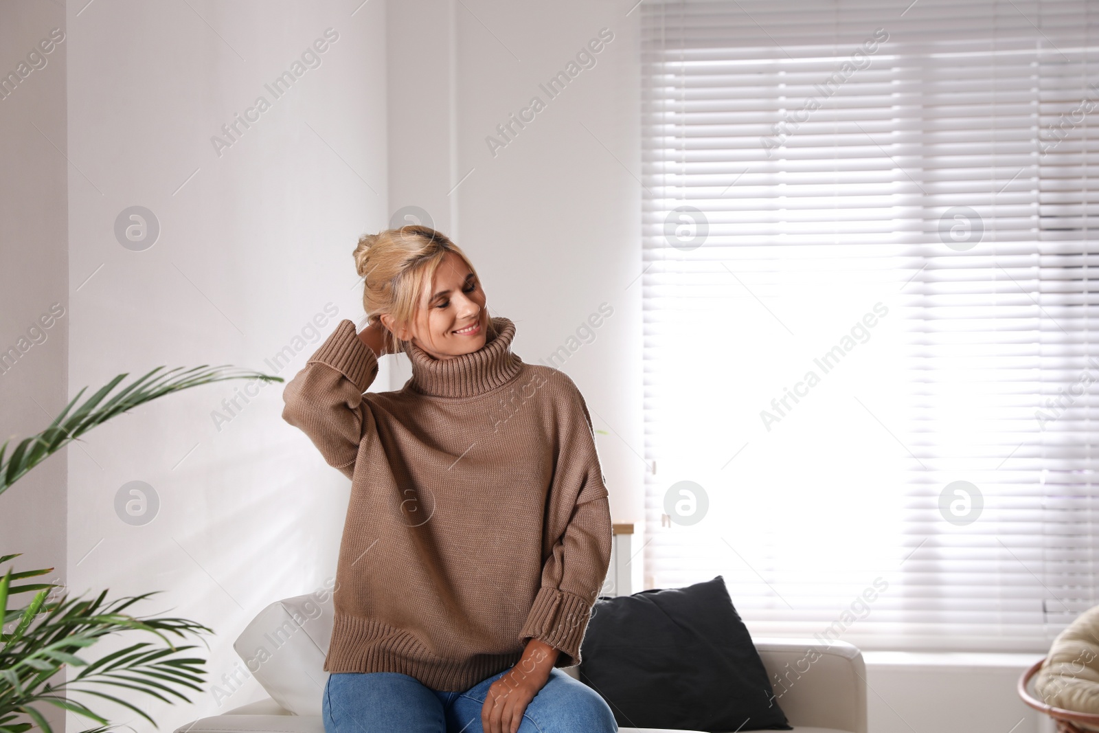 Photo of Happy woman in stylish sweater in light room