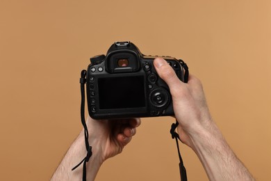 Photo of Photographer holding camera on beige background, closeup