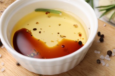Photo of Bowl of organic balsamic vinegar with oil and spices on wooden board, closeup
