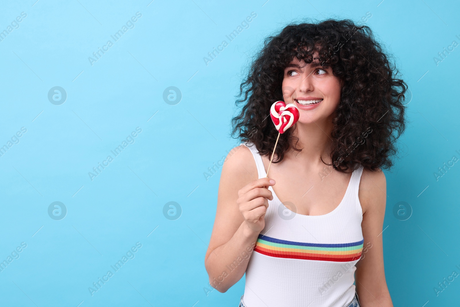 Photo of Beautiful woman with lollipop on light blue background, space for text