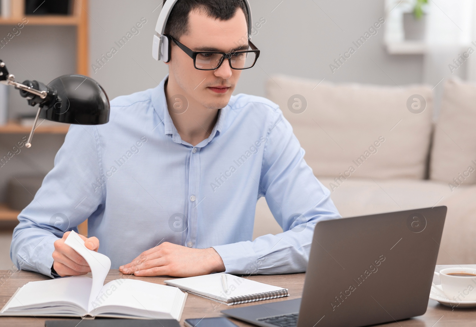 Photo of E-learning. Young man using laptop during online lesson at table indoors.