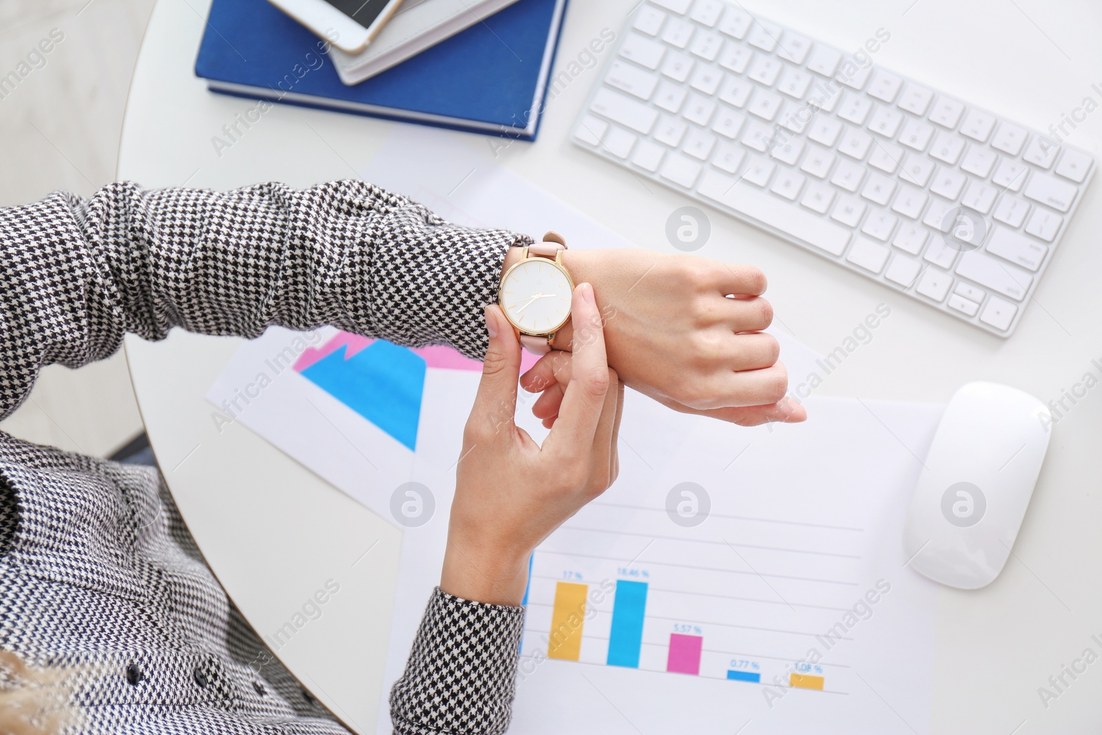 Photo of Young businesswoman checking time on her wristwatch at workplace, top view. Time management