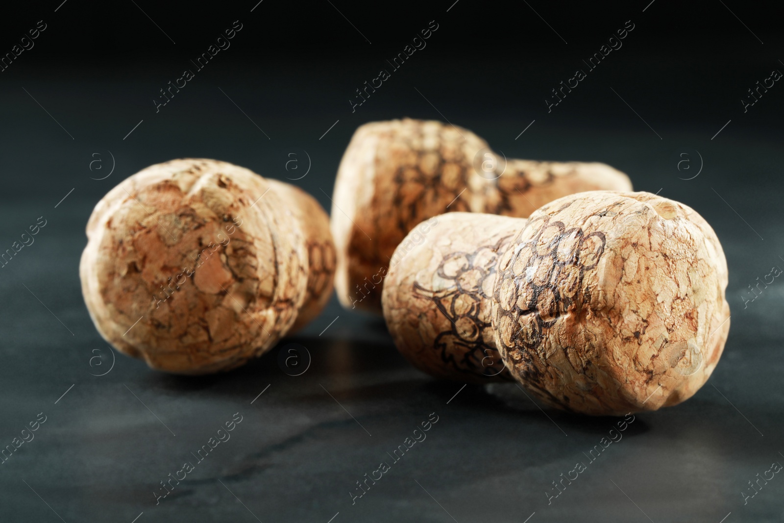 Photo of Corks of wine bottles with grape images on black table, closeup