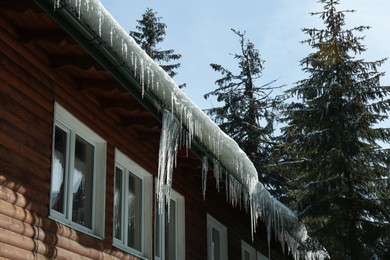 House with icicles on roof, low angle view. Winter season