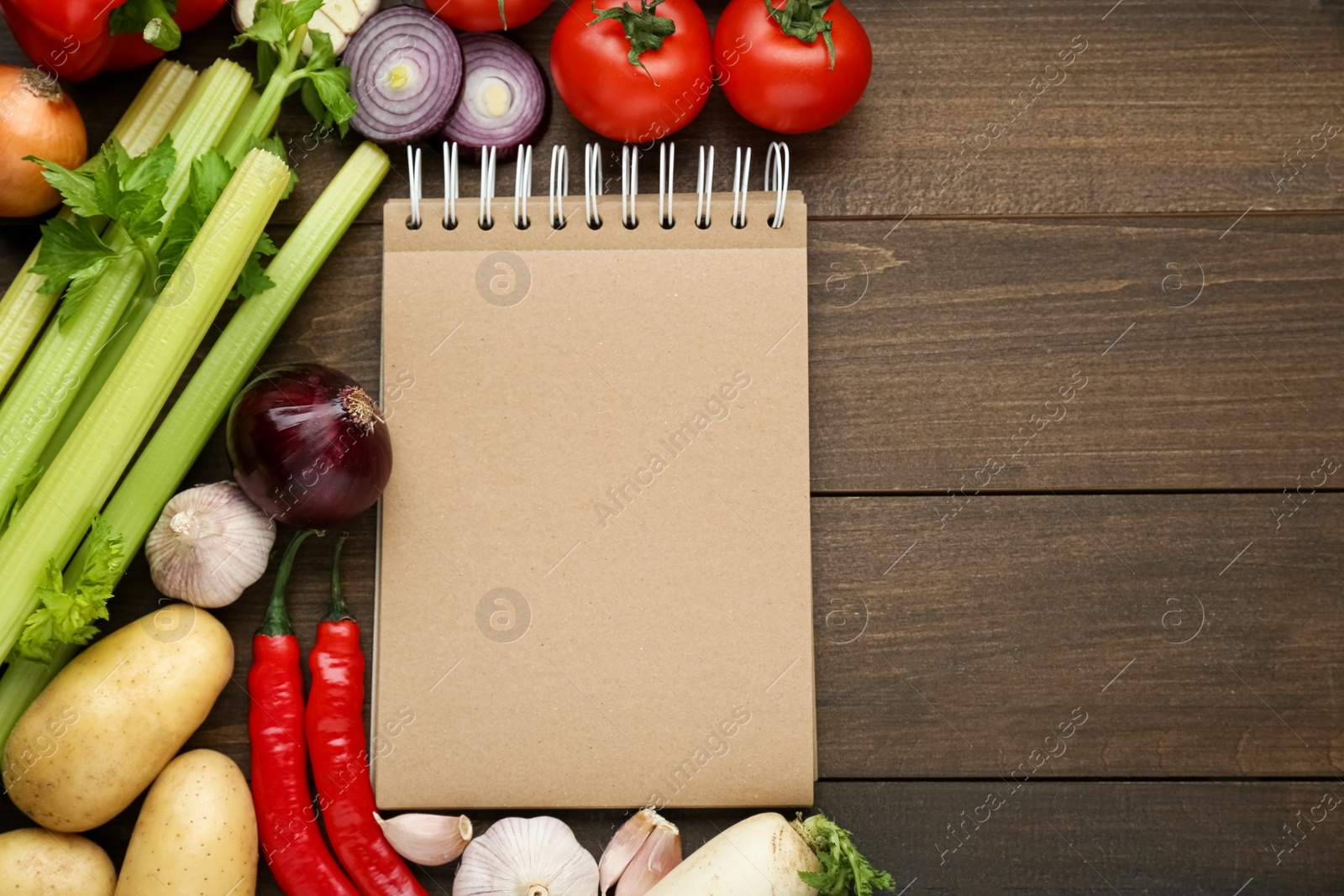 Photo of Blank recipe book and different ingredients on wooden table, flat lay. Space for text