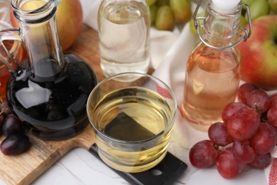 Photo of Different types of vinegar and fresh fruits on white table